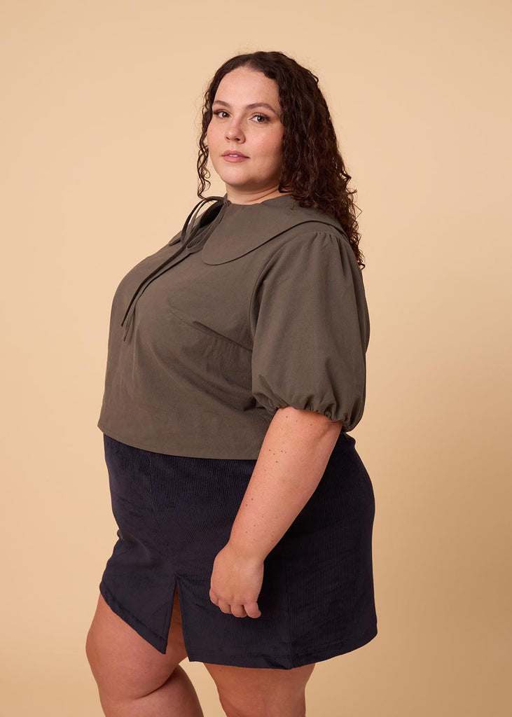 a plus size woman in an olive green blouse with an exaggerated collar