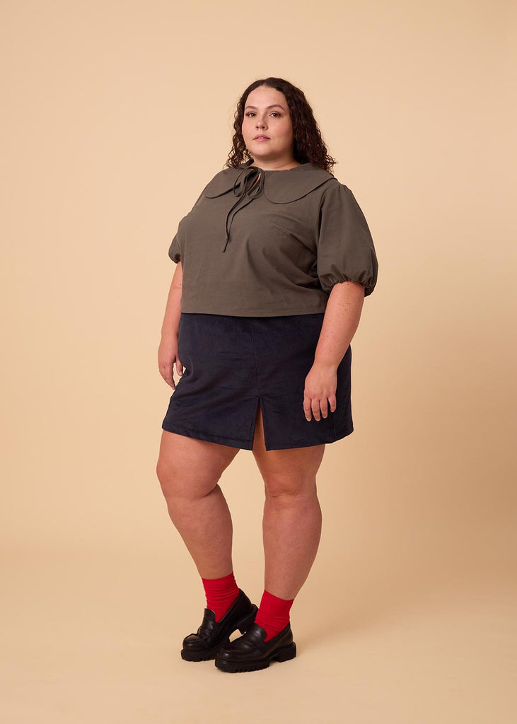 a plus size woman in an olive green blouse with an exaggerated collar