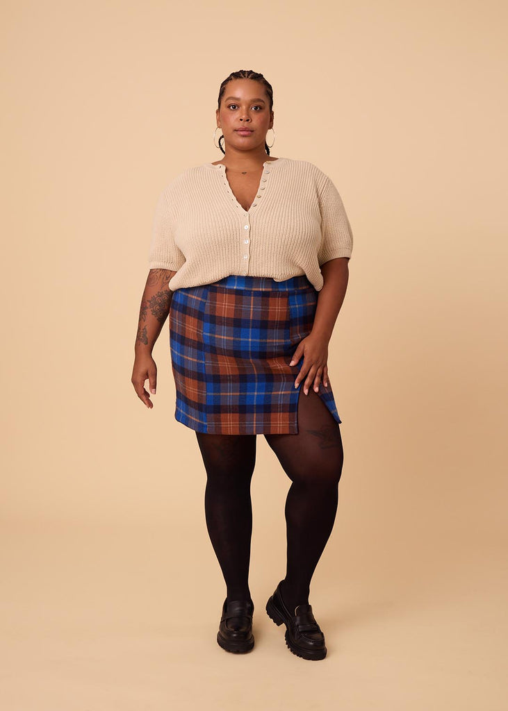 a close up of a plus sized woman wearing a plaid miniskirt