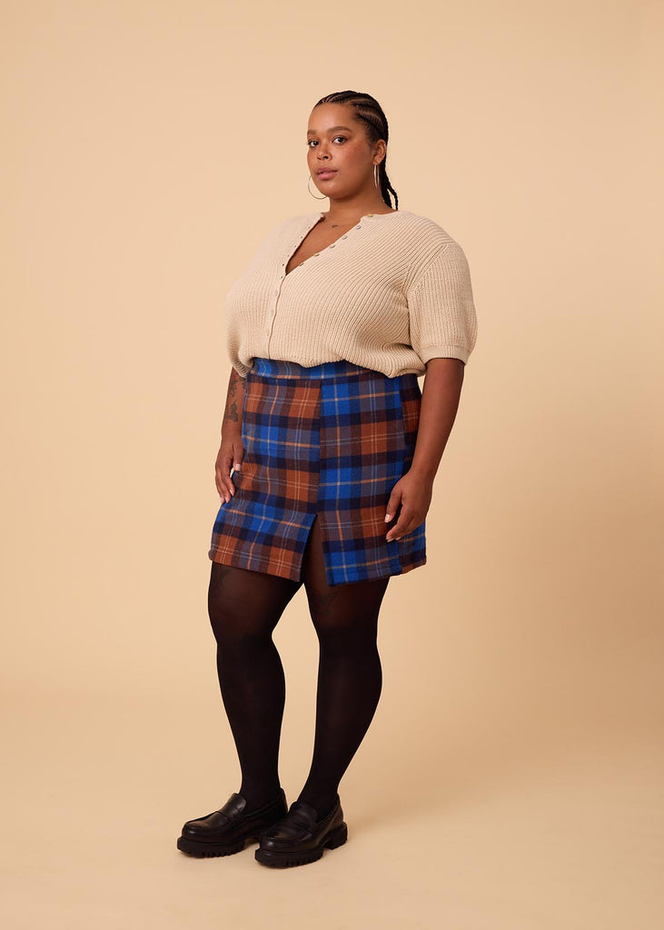 a close up of a plus sized woman wearing a plaid miniskirt