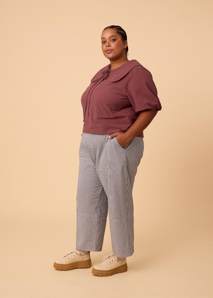 a plus size woman in a plum blouse with an exaggerated collar