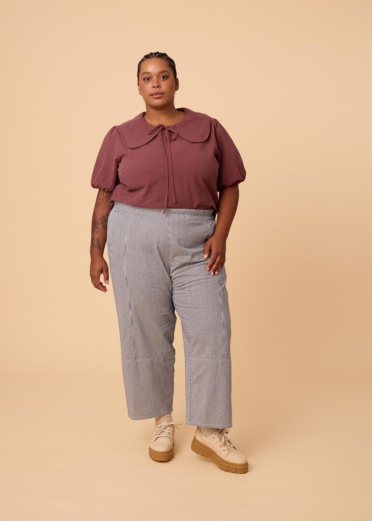 a plus size woman in a plum blouse with an exaggerated collar