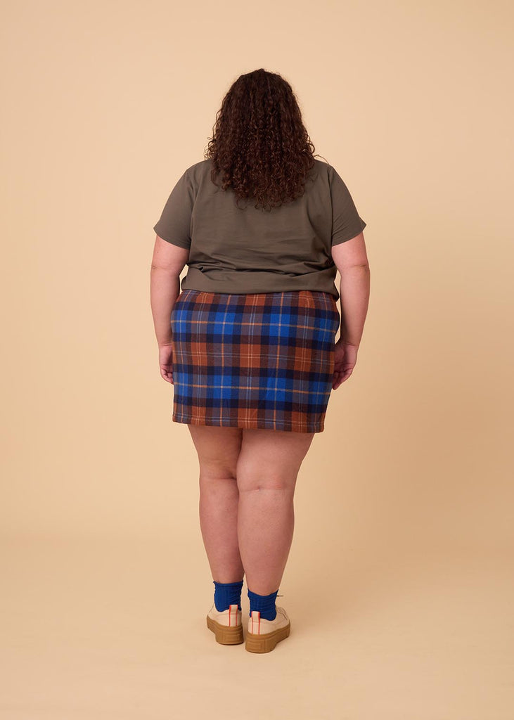 a close up of a plus sized woman wearing a plaid miniskirt