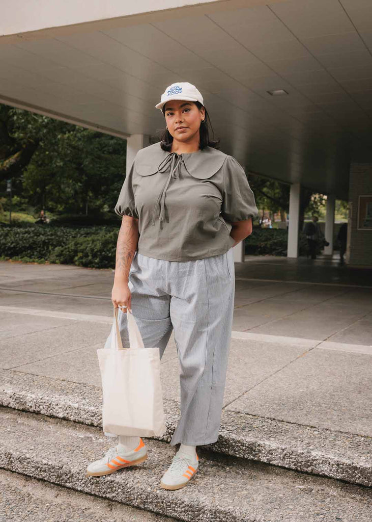 a plus size woman in an olive green blouse with an exaggerated collar