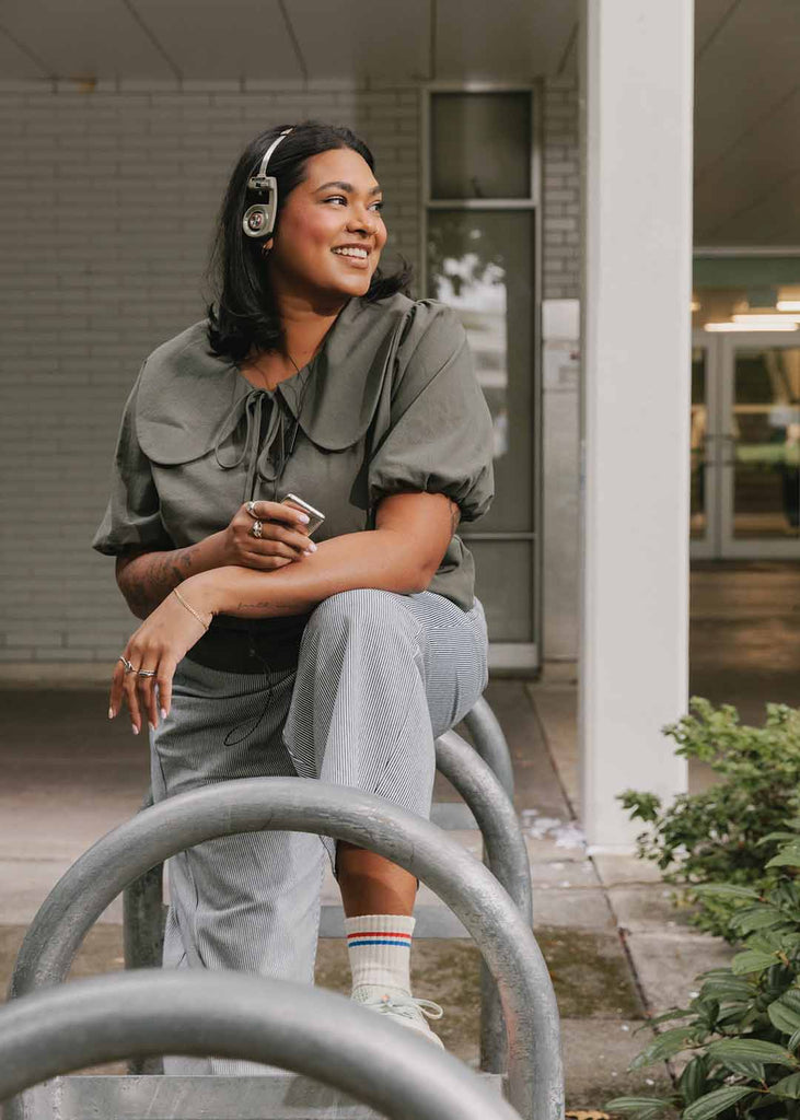 a plus size woman in an olive green blouse with an exaggerated collar