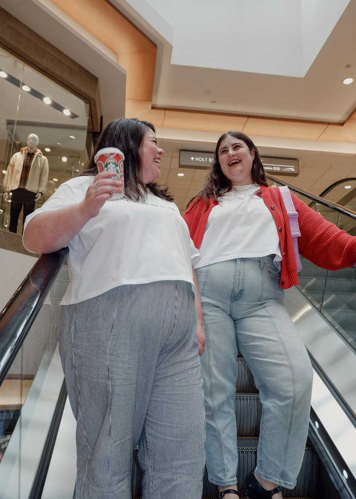 two plus size women wearing white cropped graphic tees