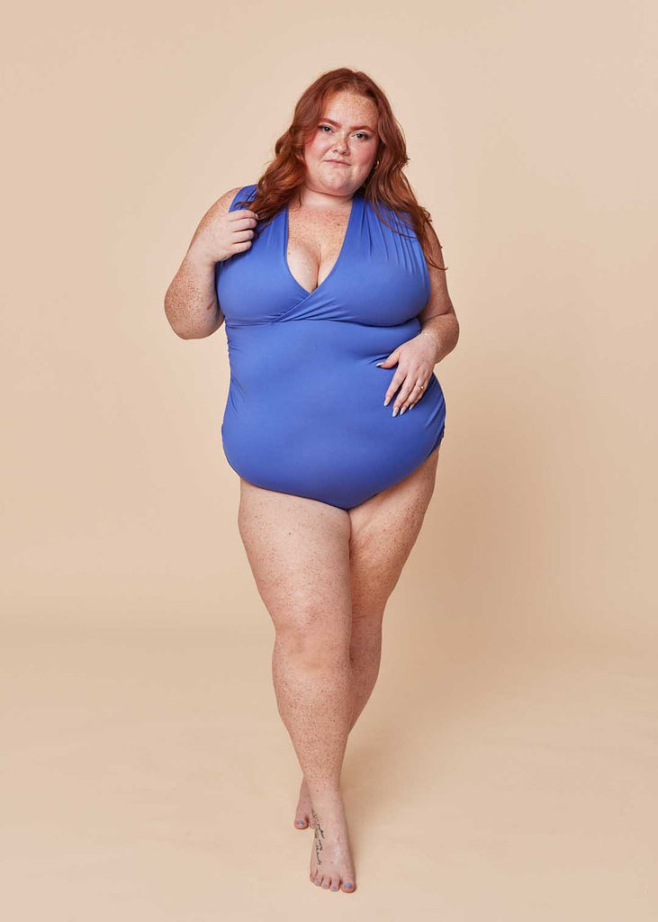 a plus size woman wearing a purple one piece swimsuit