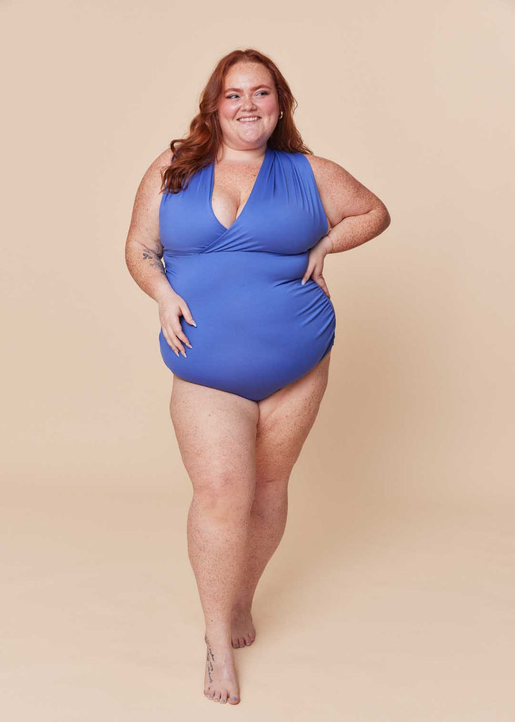 a plus size woman wearing a purple one piece swimsuit