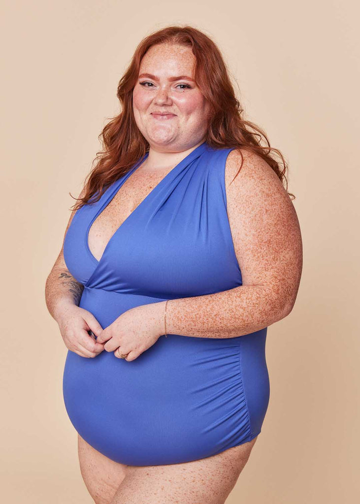 a plus size woman wearing a purple one piece swimsuit