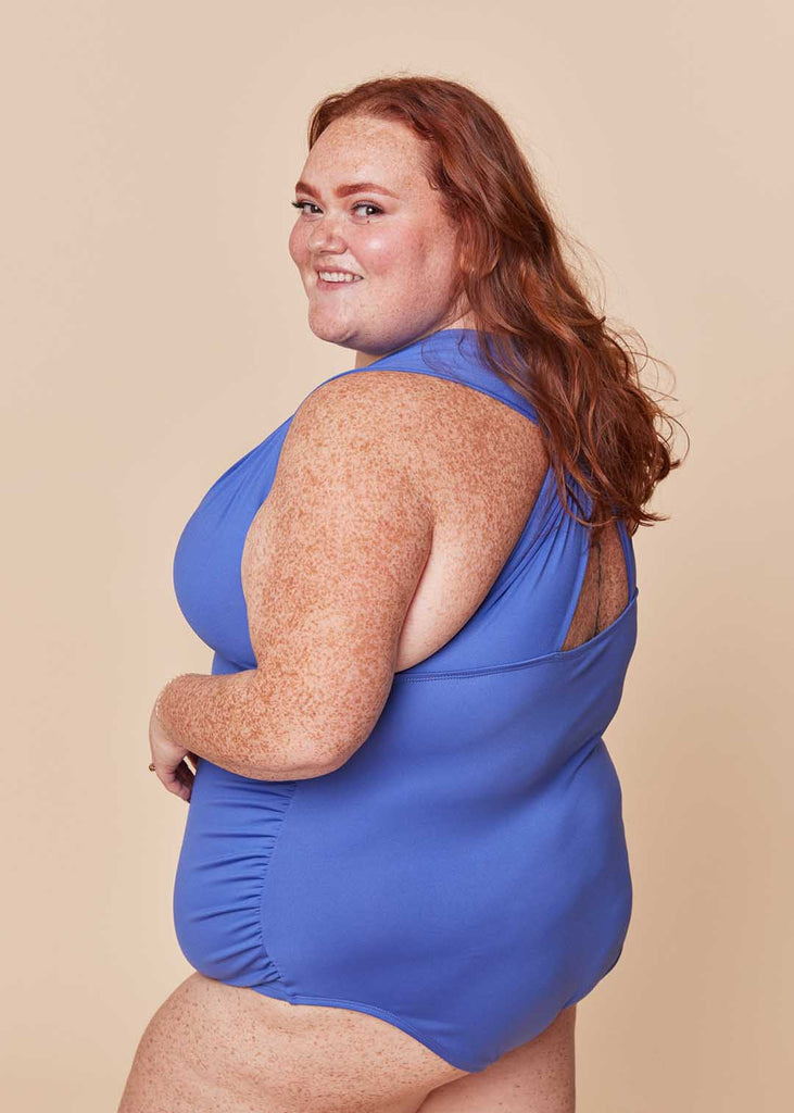 a plus size woman wearing a purple one piece swimsuit