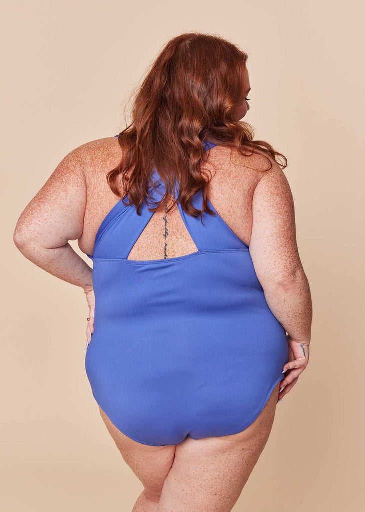 a plus size woman wearing a purple one piece swimsuit