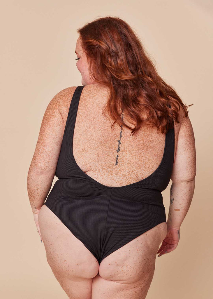 a plus size woman in a black one piece swimsuit