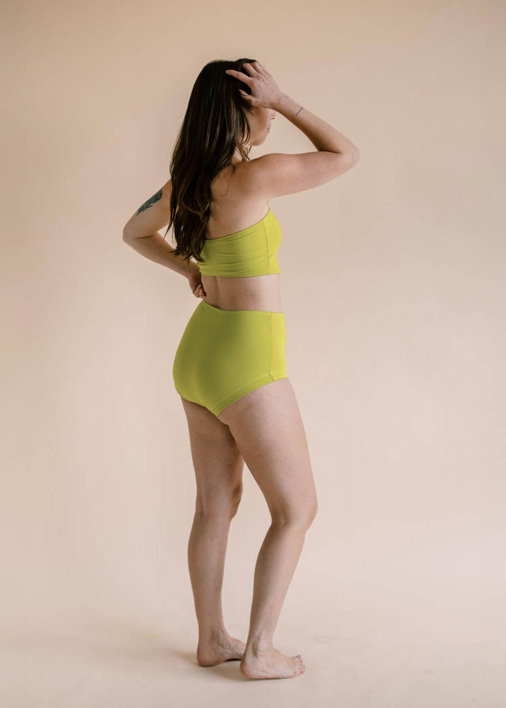 a straight sized woman wearing a green matching bandeau and underwear set