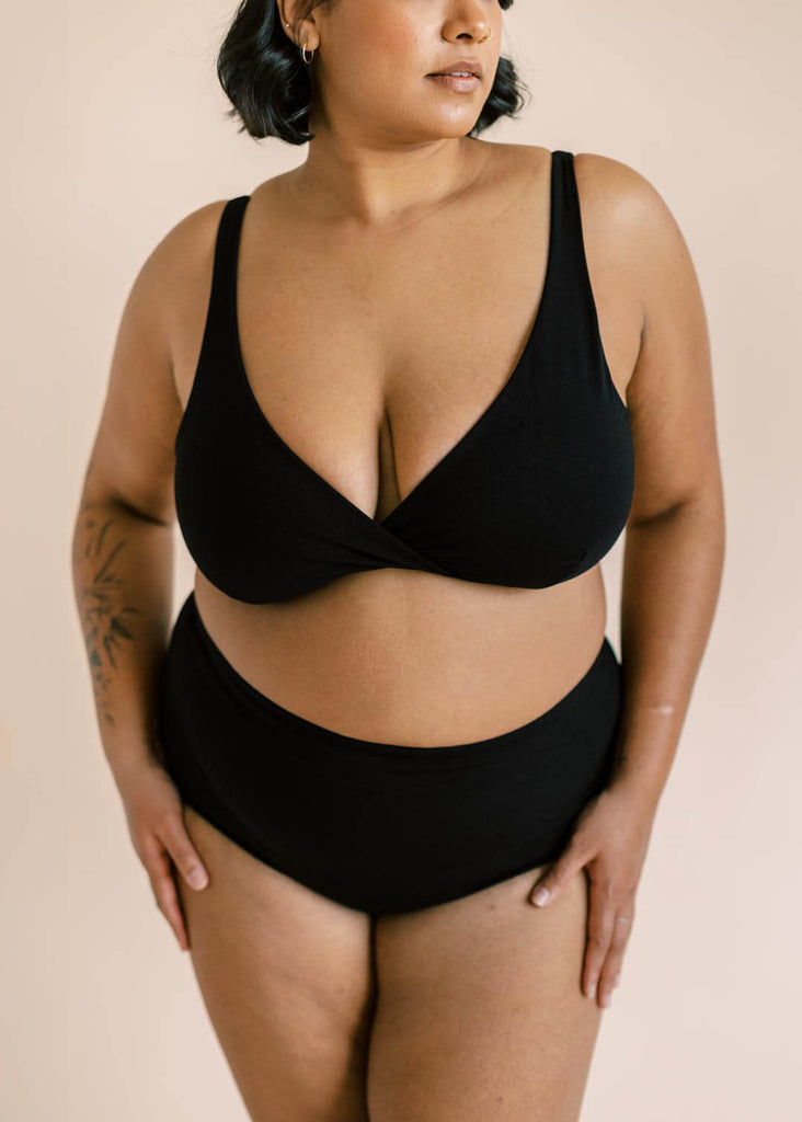 a close up of a plus sized woman wearing a black matching bra and underwear set