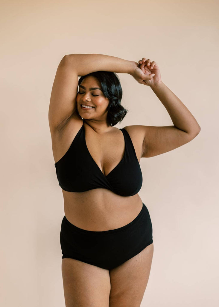 a plus sized woman wearing a black matching bra and underwear set