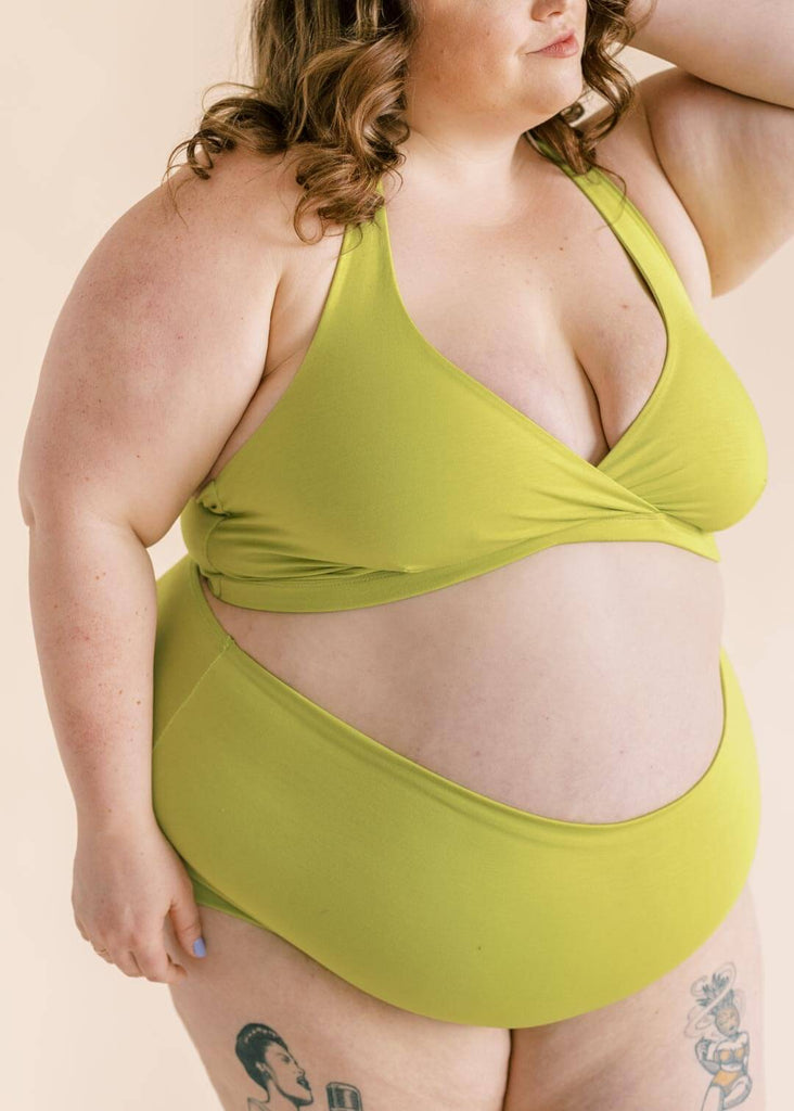 a close up of a plus sized woman wearing a green matching bra and underwear set