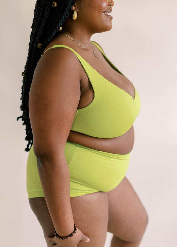 a close up of a mid sized woman wearing a green matching bra and underwear set