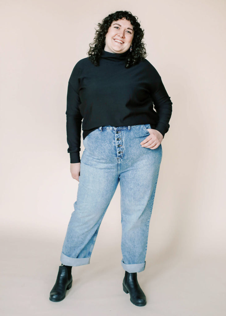 a plus size woman wearing a black roll neck sweatshirt