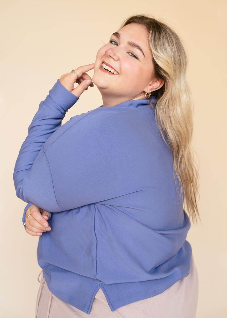 a plus size woman wearing a  blue rollneck sweatshirt