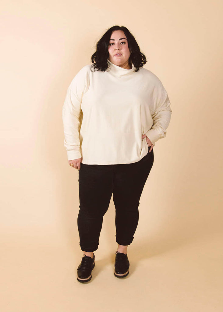 a plus size woman wearing a cream roll neck sweatshirt