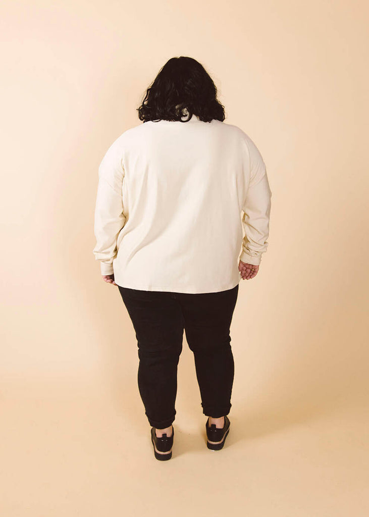 a plus size woman wearing a cream roll neck sweatshirt